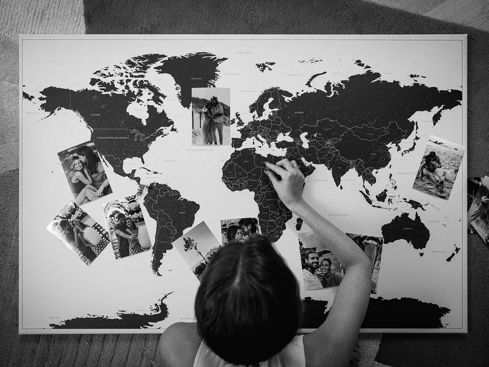 Hände pinnen Fotos auf eine Weltkarte bei einer Social-Content-Produktion