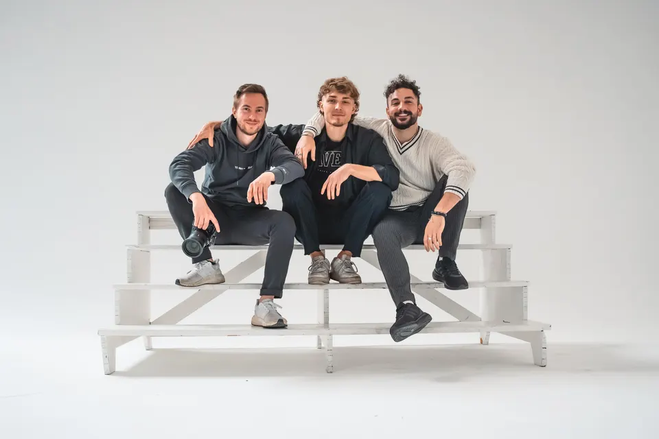 Drei Mitglieder des GetTheShot-Teams auf einer weißen Treppe im Studio