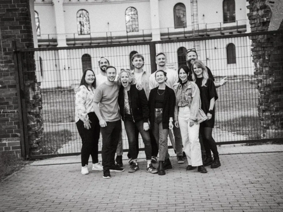 Gruppenfoto der Crew vor einem schmiedeeisernen Tor, Schwarzweiß