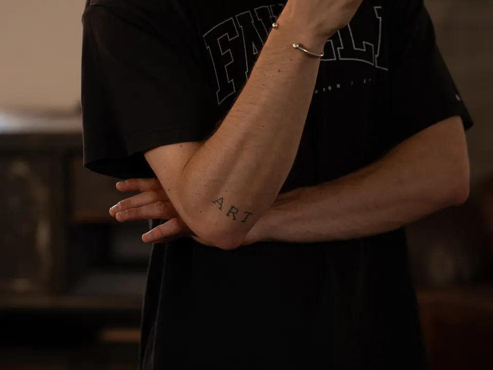 Detailaufnahme verschränkter Arme mit Tattoo